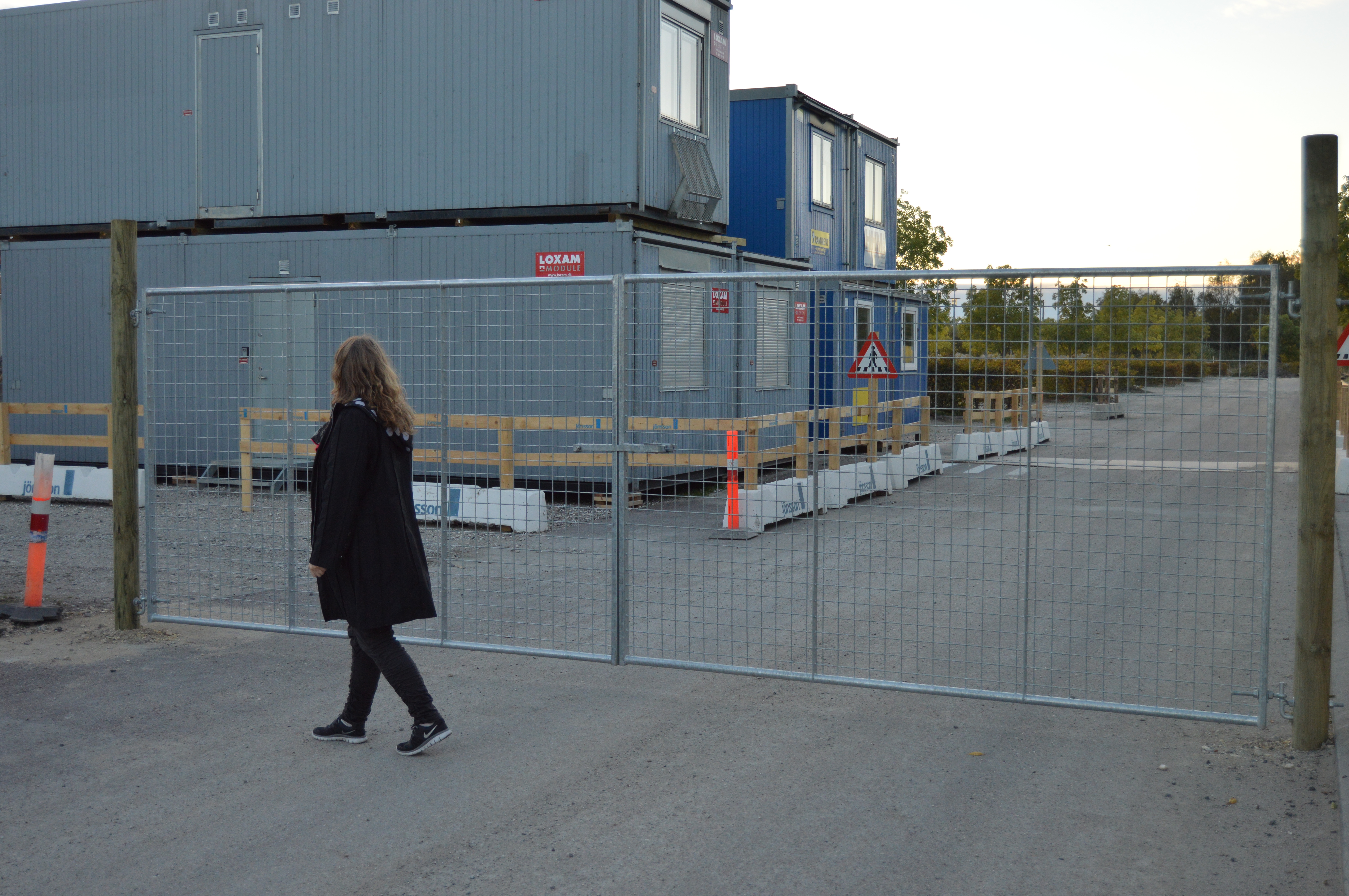 En kvinna går framför en lättviktsgrind som installerats på en byggarbetsplats