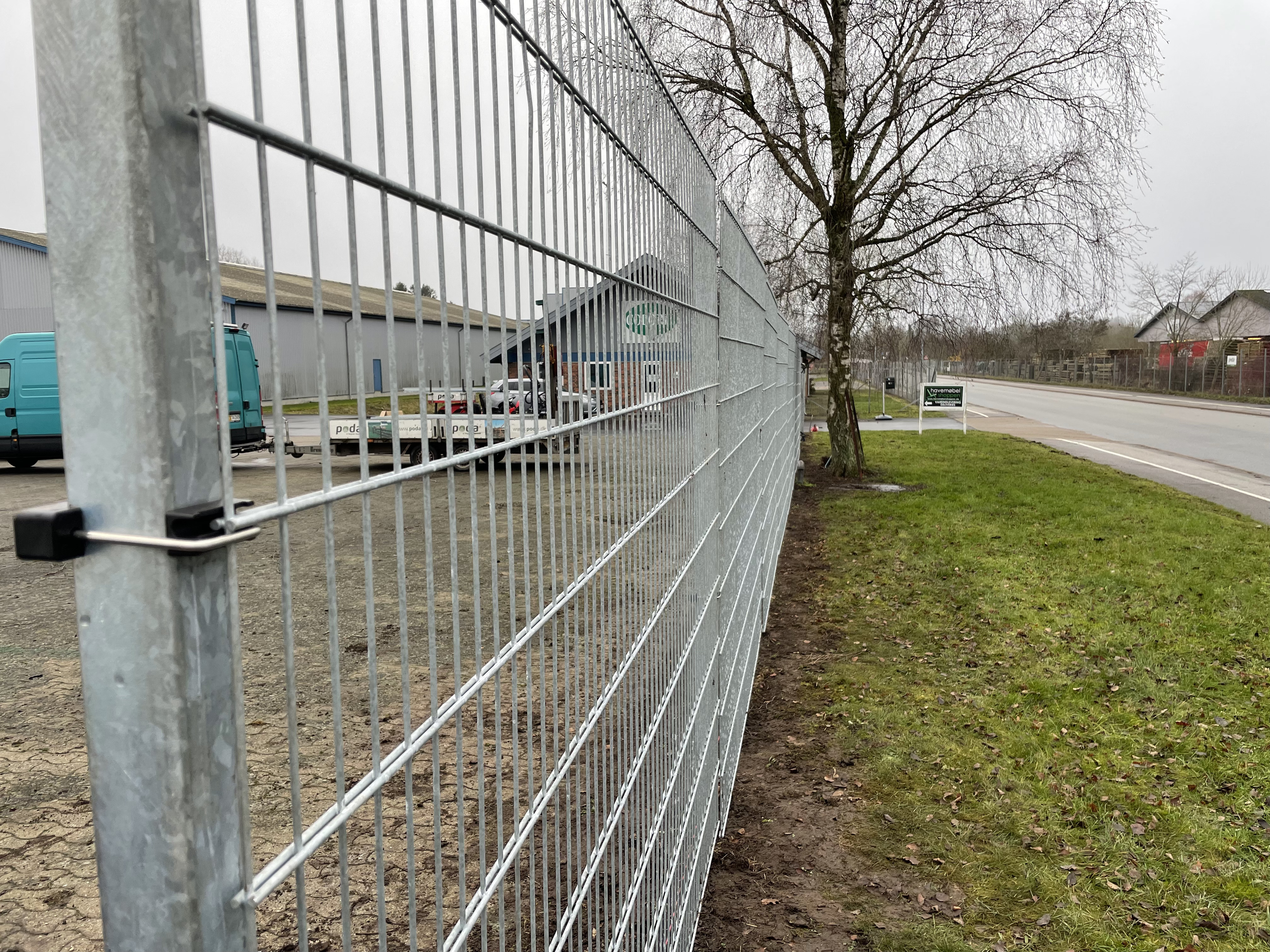 I ett industriområde har ett stängsel med grå panel installerats för att skydda ett företag